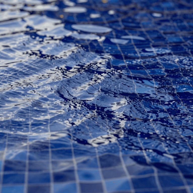 A wide shot of a modern infinity pool with #1B263B blue water blending into the horizon, minimalist design.