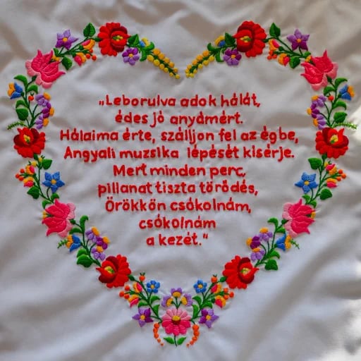 Kalocsai hímzés fehér textilen, piros hímzett szöveggel..