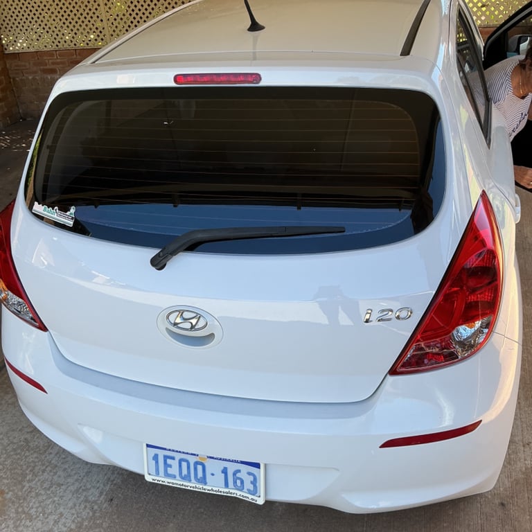Rear view of a white Hyundai i20 hatchback parked in a driveway following peeling paint repair.