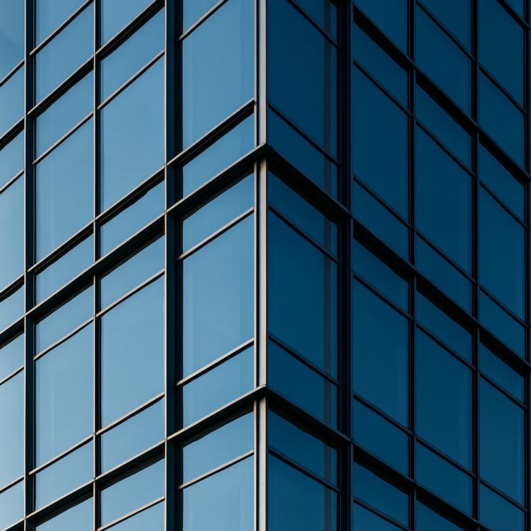 Minimalist architectural detail of a modern office building exterior with glass panels and steel beams, reflecting a clear sky.