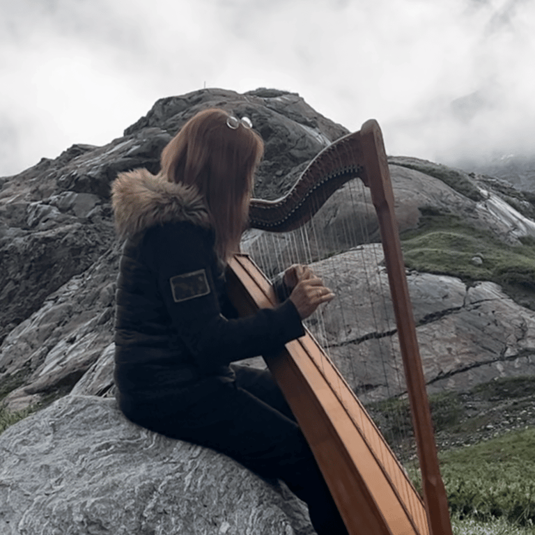 a woman playing a harpet on a rock