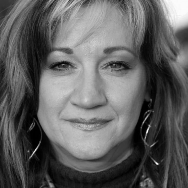 A black and white photo of a middle-aged Caucasian woman with long layered hair