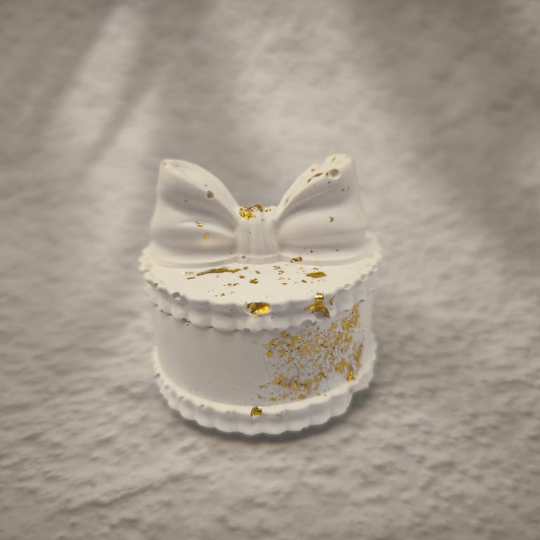 Balta papuošalų dėžutė su kaspino formos dangteliu ir auksinėmis detalėmis