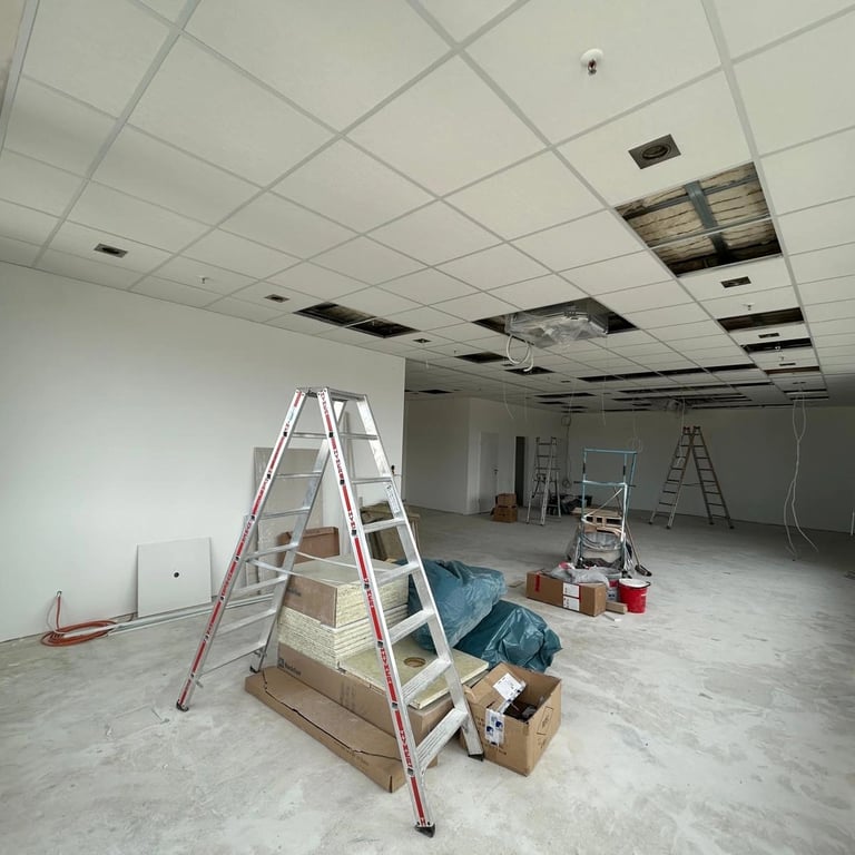 Sufit kasetonowy w trakcie montażu, duża sala z rusztowaniem i czarnymi panelami akustycznymi, płyty sufitowe w układzie pros