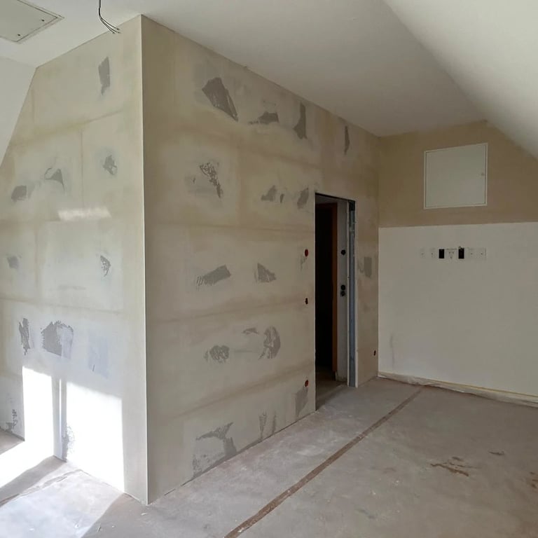 Ściana działowa na poddaszu, płyty gipsowe w trakcie wykończenia, otwór na drzwi.