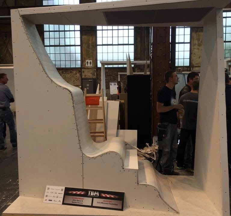 Niestandardowa zabudowa z płyt gipsowych w formie dużej, łukowej konstrukcji z siedziskiem i zadaszeniem, montaż w przestrzen