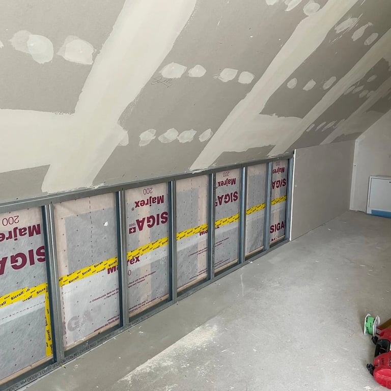 Montaż zabudowy poddasza, widoczne profile metalowe, izolacja akustyczna i przygotowanie ścian pod płyty gipsowe.