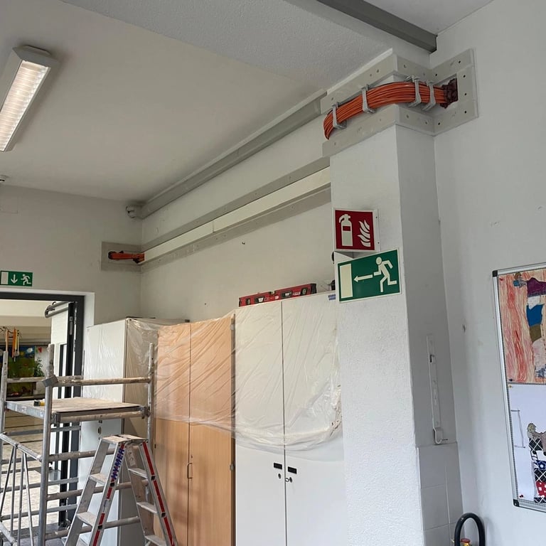 Montaż zabudowy przeciwogniowej wokół instalacji kablowej, widoczne pomarańczowe przewody i konstrukcja z płyt ognioodpornych