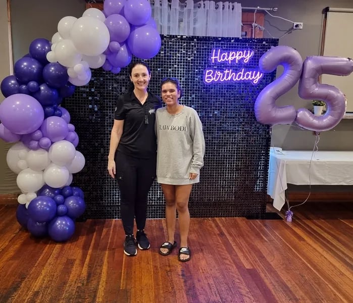 Carly and Jamila having a photo in front of his black shimmer wall and garland in Cleveland.