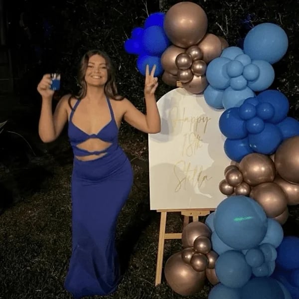 Stella beside her balloons with a cup of blue slushie poured from her SweetAz slushie machine.