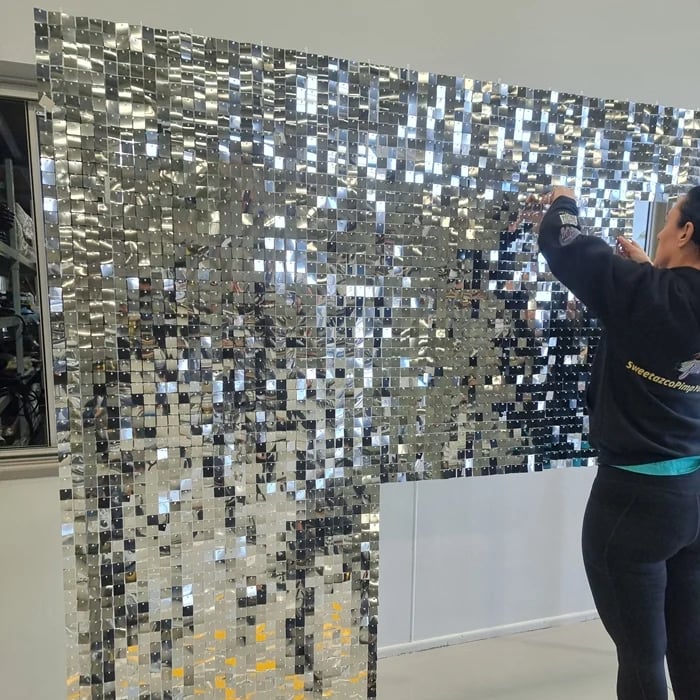 SweetAz Co. setting up the silver shimmer wall in the massive warehouse for a 50th birthday.