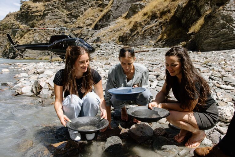 Gold Panning in Central Otago at one of Otago Gold's Claims, three young women panning and a helicopter in the background