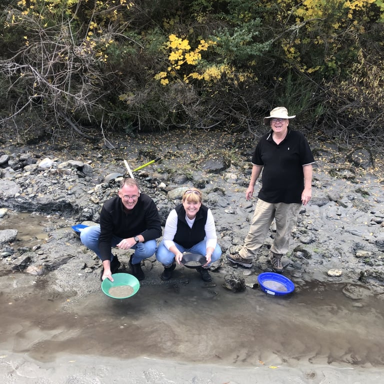 A photograph of a group of people, panning for gold on a river in Central Otago, New Zealand.