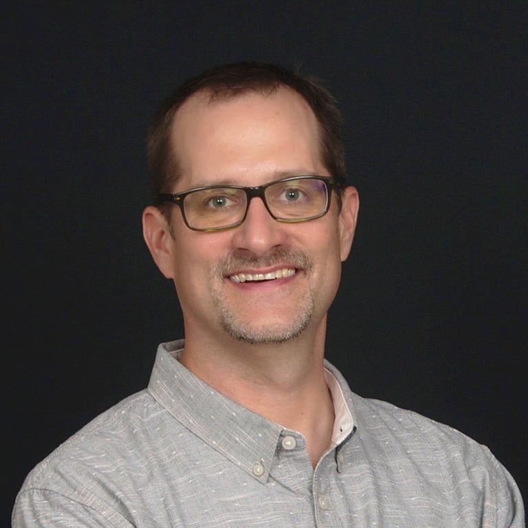 Jim Kalbach, a man with glasses and a gray shirt button up shirt 