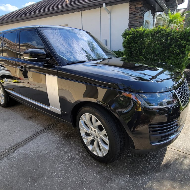 A black Ranger rover SUV ina tampa bay drive way surrounded by mobile detailing equipment