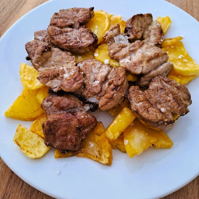 Castañuelas con patatas presentadas en la galería del Bar Las Tinajas Huelva, mostrando un plato tradicional y apetecible.