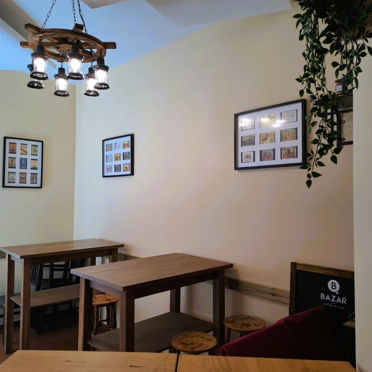 Zona interior del Bar Las Tinajas Huelva, con mesas altas, cuadros en la pared, lámpara colgante y planta decorativa.