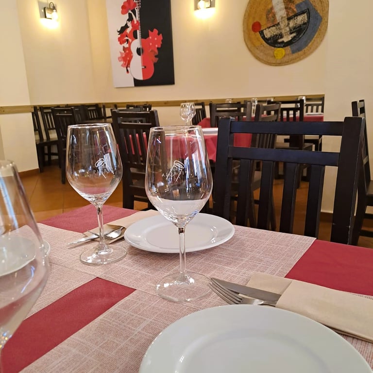 Interior que representa la Historia del Bar Las Tinajas Huelva, con mesas preparadas y un cuadro decorativo al fondo.