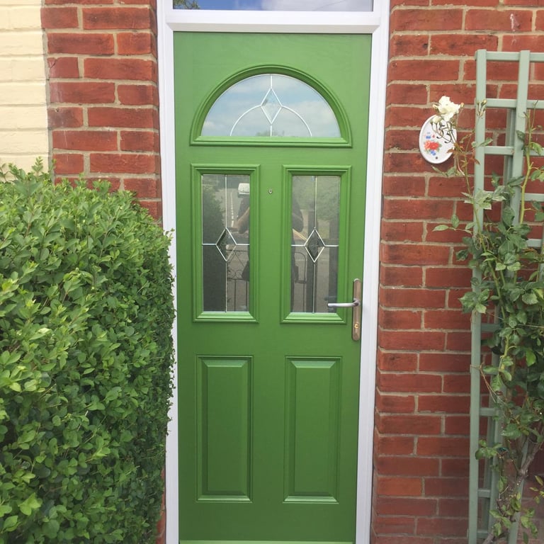 a bespoke bright green front door with diamond lead glass. there are three windows on the door