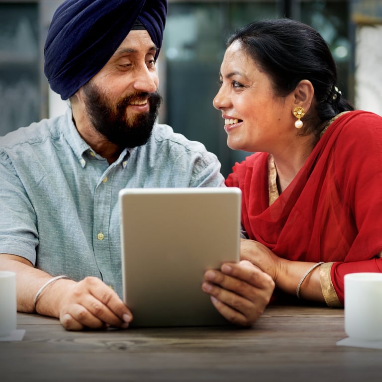 a man and woman sitting at a table with a iPad in their hands looking at each other