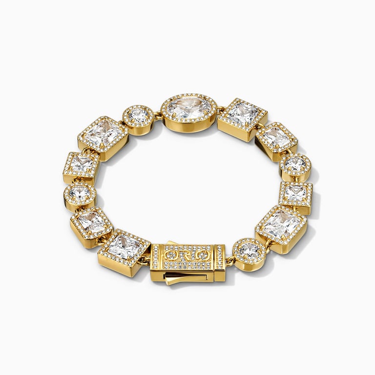 Studio shot of a round gold tennis bracelet with alternating oval and square cubic zirconia stones and a clasp.
