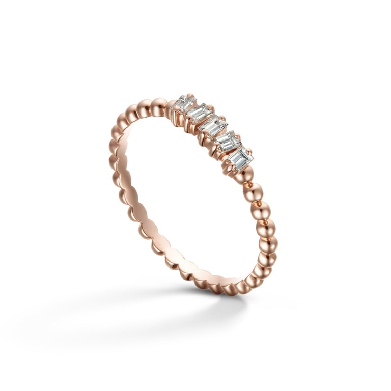 Delicate rose gold ring with beaded band and sparkling baguette diamonds displayed on a clean white background for e-commerce