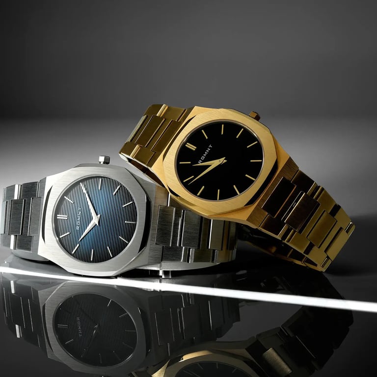 Studio product photo of two luxury watches with angular cases, one silver with a blue dial and one gold with a black dial.