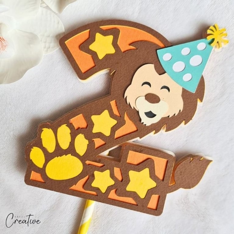 Cake topper in a shape of number 2, with lion head, paw and stars on it.