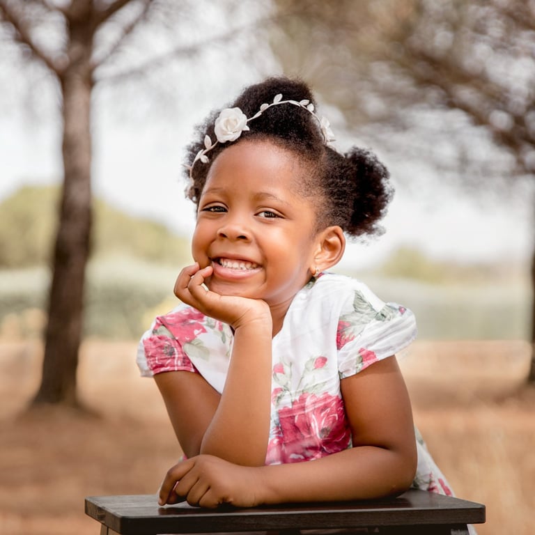 niña en el campo sujetando su cabeza con la mano y sonriendo
