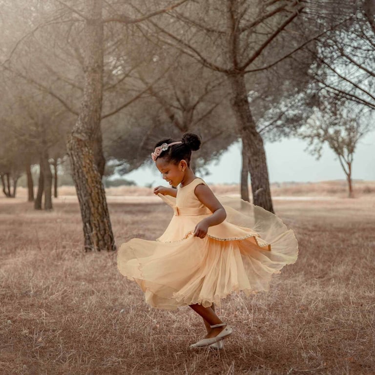 niña con vestido amarillo jugando entre los pinos