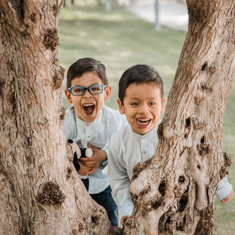 dos niños jugando detrás de un árbol