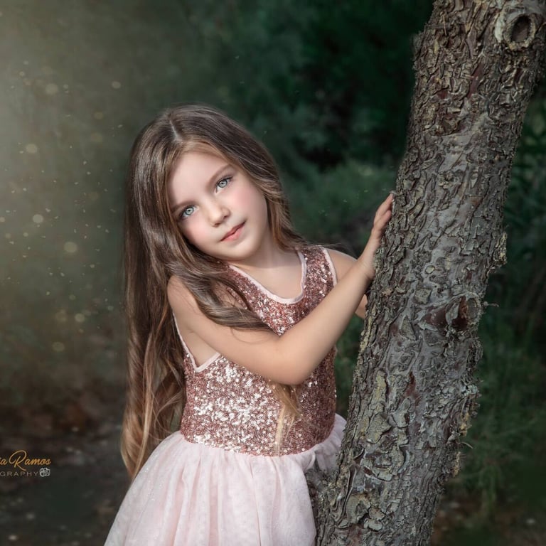 niña apoyada en el tronco de un árbol