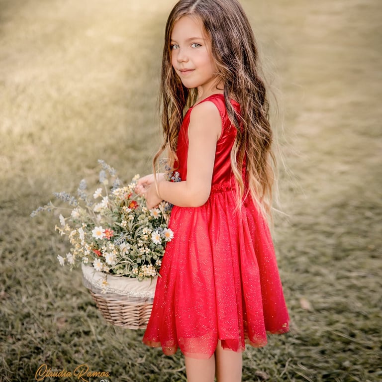 niña con vestido rojo sujetando una cesta con flores
