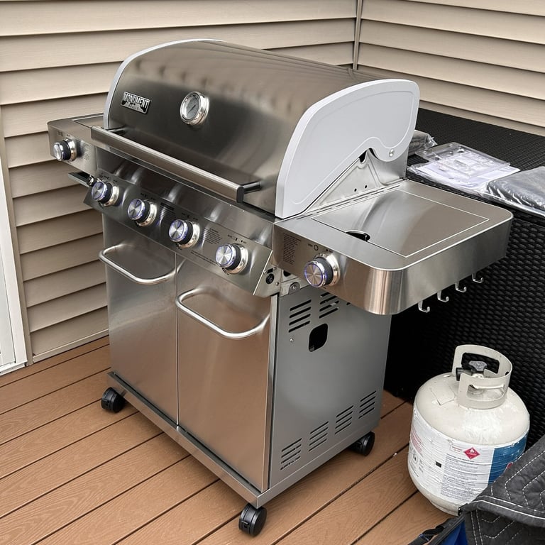 Left side view of stainless steel propane grill showing side burner and hooks