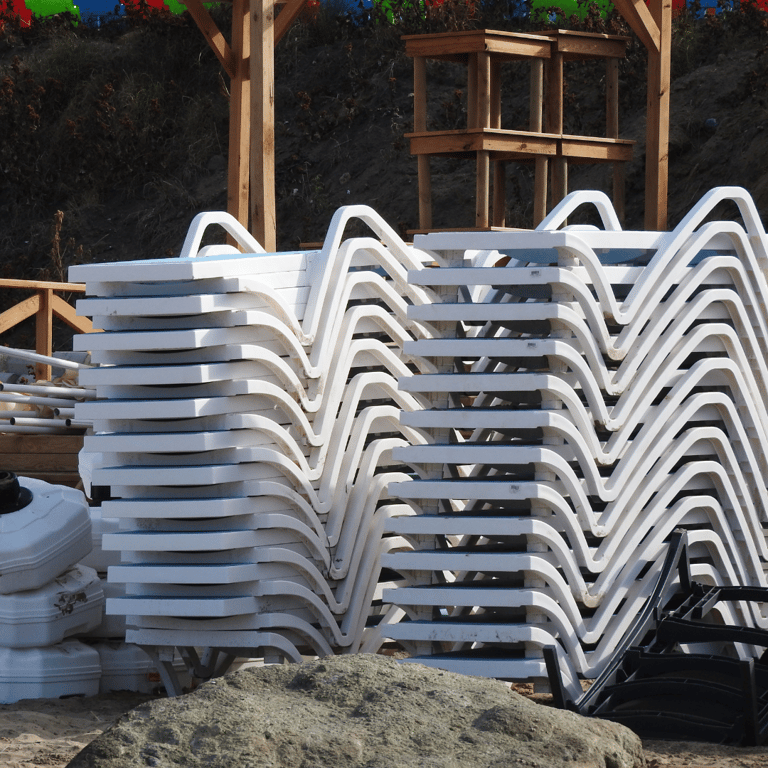 a pile of plastic chaise lounges chairs with plastic chairs