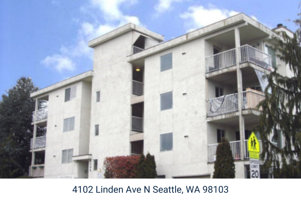 A white, low rise multi-family apartment building.