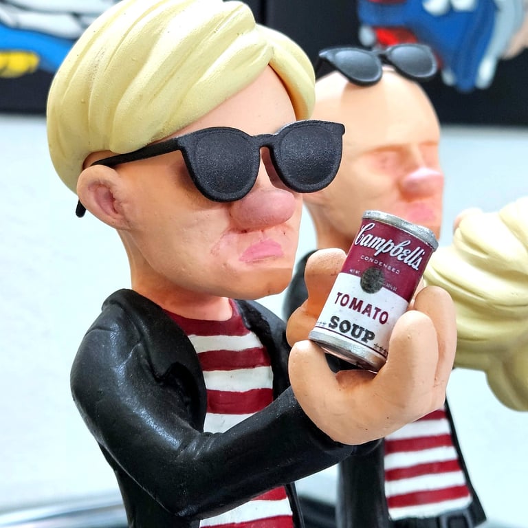 Andy Warhol caricature figurine wearing sunglasses and holding a miniature Campbell's tomato soup can.