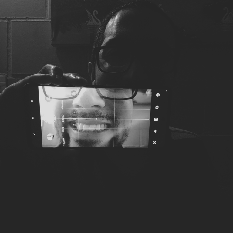 A cell phone capturing a smile in a high-contrast selfie.