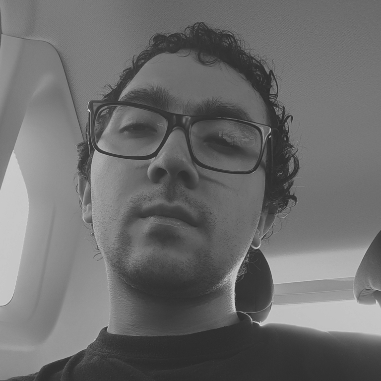 Hombre joven con gafas en blanco y negro dentro de un auto.