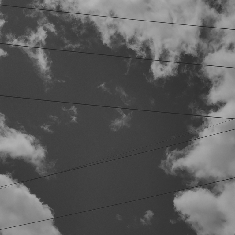 Imagen en blanco y negro de nubes y cables eléctricos.