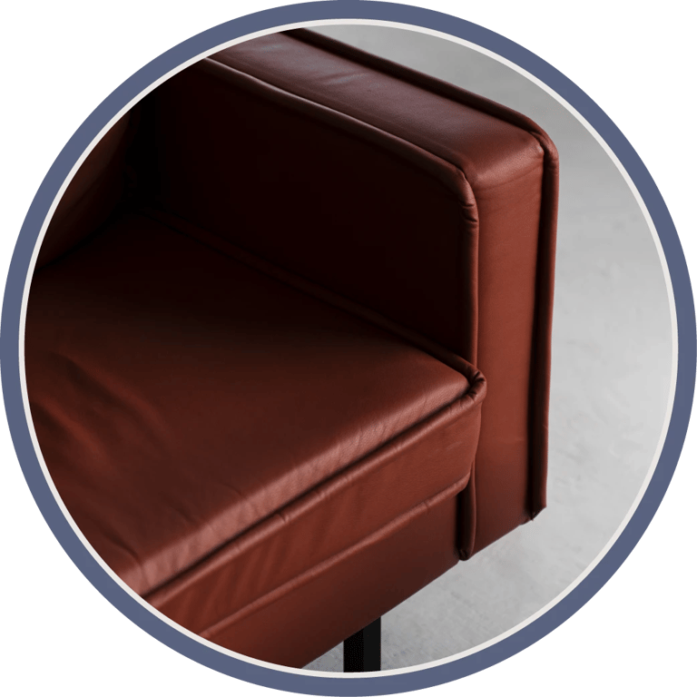 A close-up of a red-brown leather sofa, focusing on the armrest and backrest.