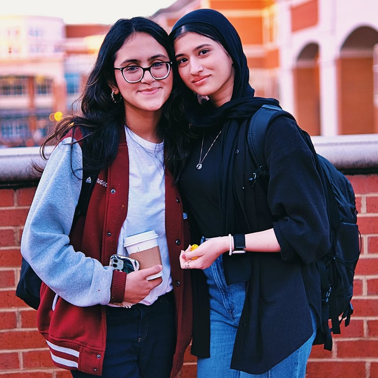 Two young college women best friends smiling at the camera.