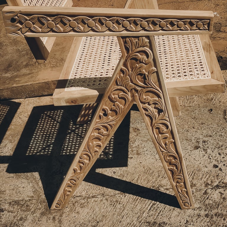 A teak wood chair featuring a combination of hand-carved wooden elements and woven rattan details.