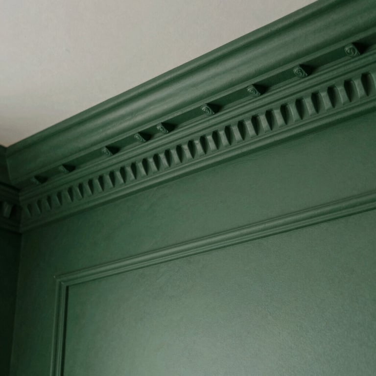 Detailed shot of custom architectural molding and a Deep Green accent wall in a modern North American residence.