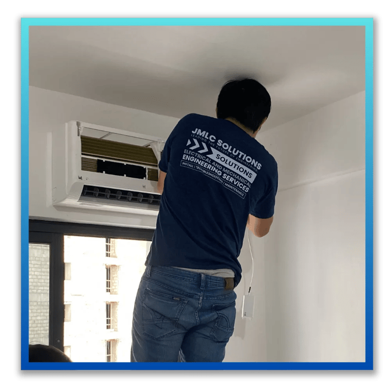 a JMLC Solutions technician in a blue uniform is installing an aircon
