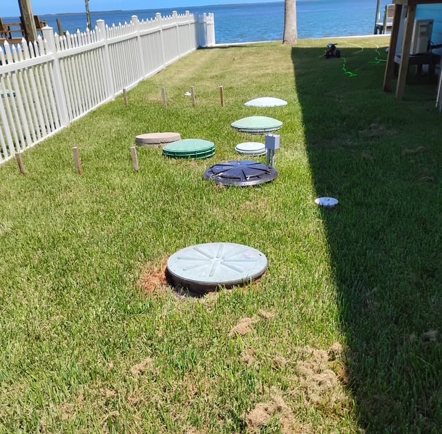 Septic system beside a stilt foundation home with coastal waters behind it
