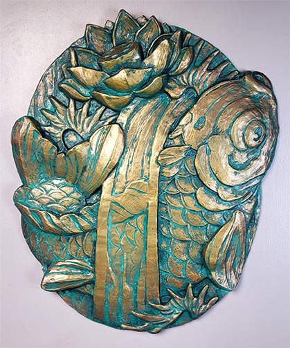 Image of a custom bronze plaque. It shows a Koi fish swimming up, surrounded by finger waves and a blooming lotus flower. 