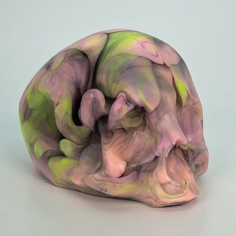 A silicone skull. It is transparent with pink and green marbling. 