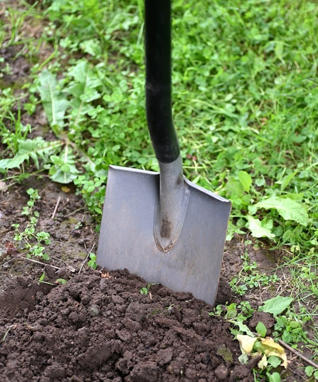 a person digging up soil with a showel