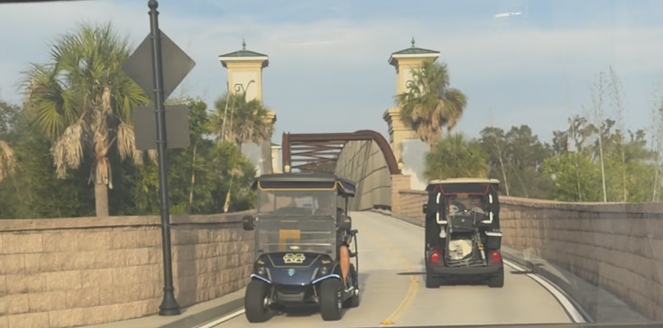 Golf cars traveling over a bridge on designated golf car paths in The Villages community